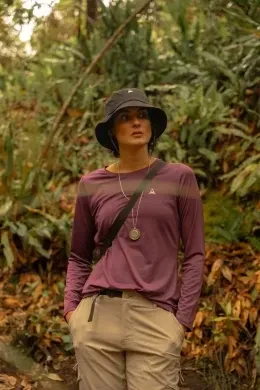Woman in a purple top and bucket hat standing amid lush forest greenery near Unika Hotels, the luxury hotels in Bogota