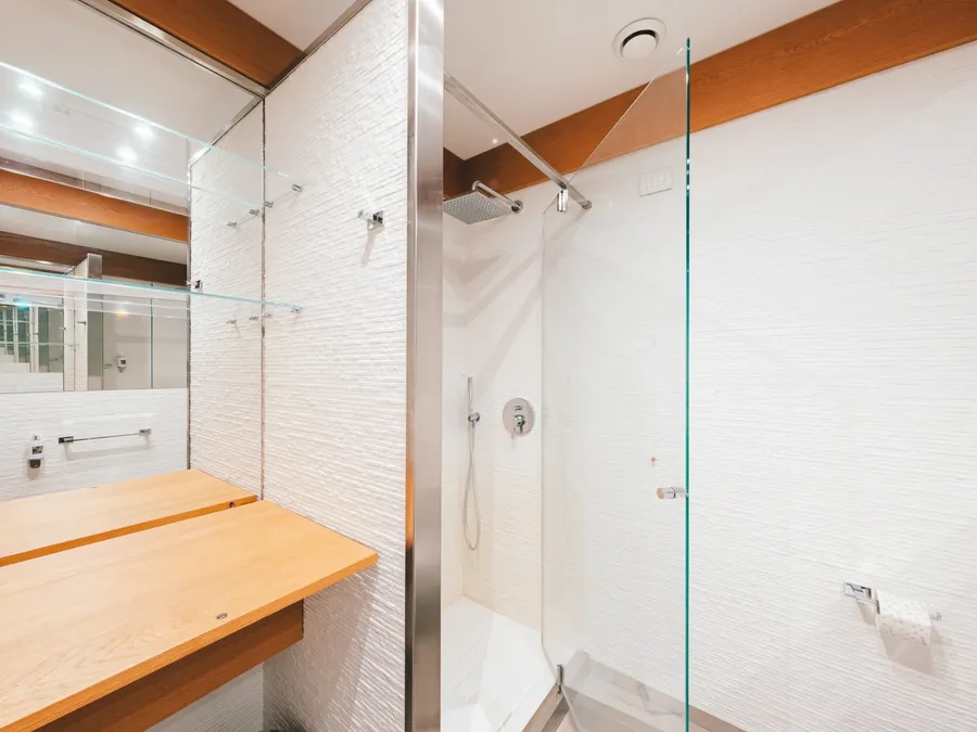 Salle de bain moderne avec douche en verre et étagère en bois à la Chambre Classique de Masseria Stali, Caprarica di Lecce.