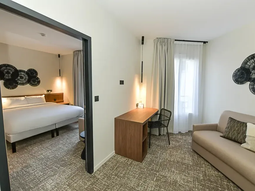 Suite familiale élégante avec un grand lit et un canapé au Hôtel Rivella à Clisson.