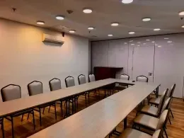 Meeting room with U-shaped tables and gray chairs beneath ceiling lights at Unika Hotels, one of the best hotels in Bogota