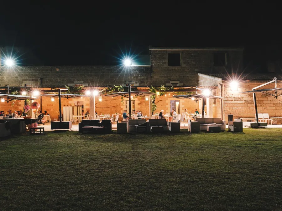 Terrasse de Masseria Stali éclairée la nuit avec des invités.