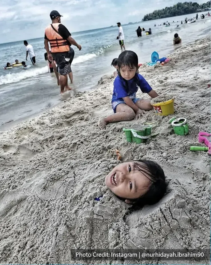 Kids playing with sand at Teluk Kemang Beach