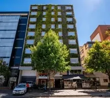 Exterior of Hotel B3 Virrey with green facade and trees along the street near Unika Hotels, one of the best hotels in Bogota