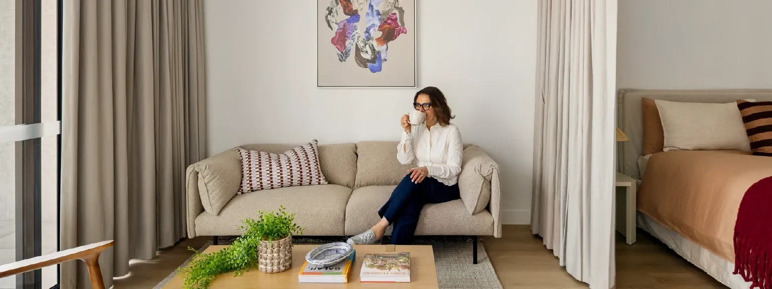 Woman relaxing on a couch with a coffee in Studio Apartment at Swift Walk in Kensington.