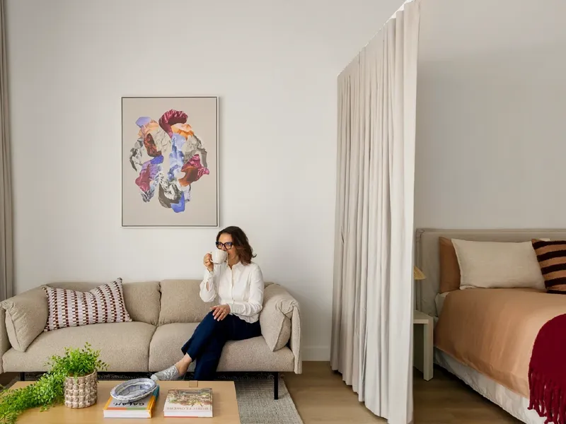 Woman relaxing on a couch with a coffee in Studio Apartment at Swift Walk in Kensington.