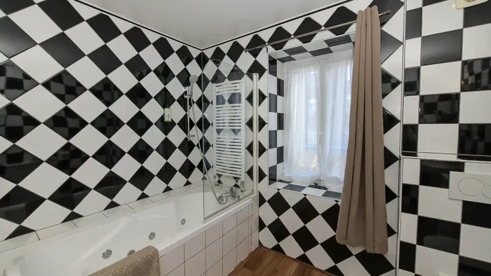 Salle de bain élégante avec carrelage en damier et baignoire à Hôtel Villa Aultia.