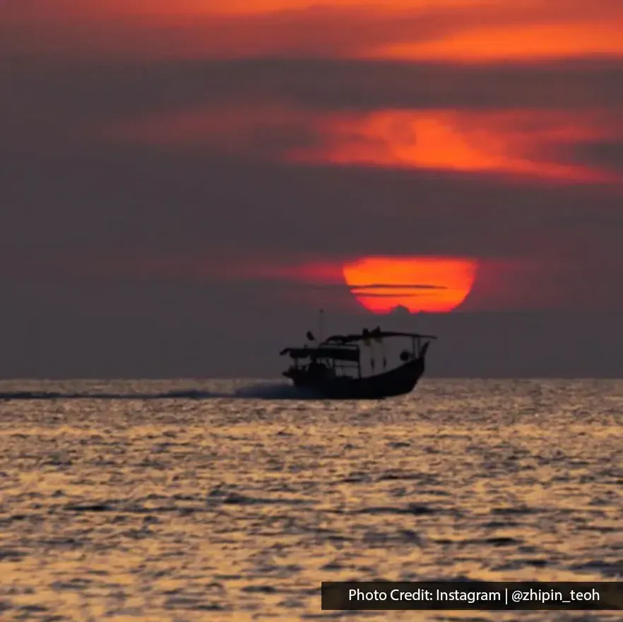 Fishing boat sailing across the sea during sunset at Sungai Batu Belah
