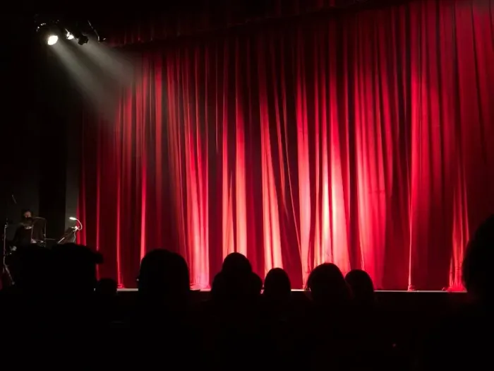 Audience watching a performer on stage with red curtain at The View Hotel Eastbourne