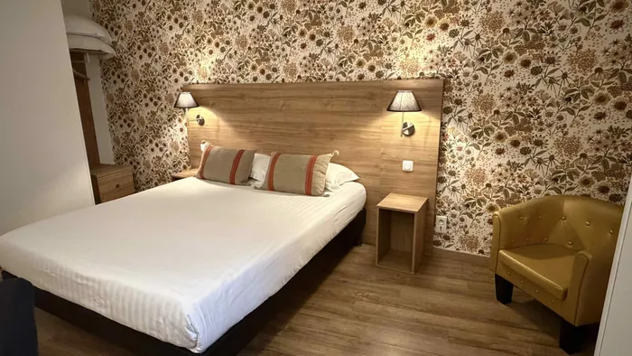 Chambre élégante avec lit double, lampes, et chaise dorée au Grand Hôtel Molière.