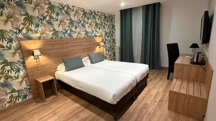 Chambre avec deux lits, bureau et télévision au Grand Hôtel Molière.