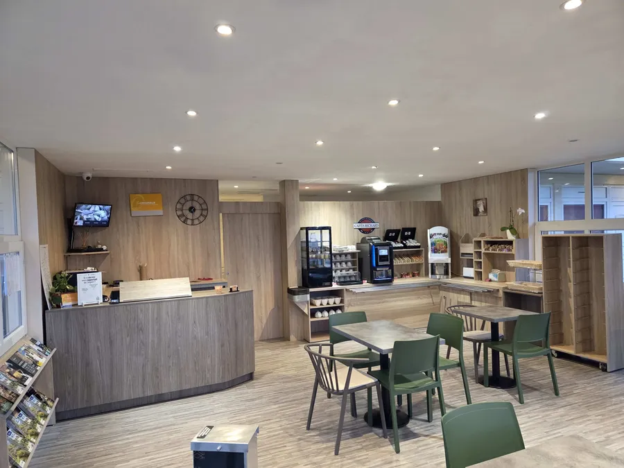 Salon de café avec tables et chaises vertes au Hôtel Aurillac Aéroport.