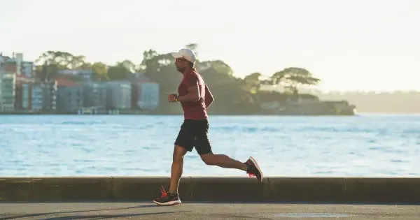  man in hat and shorts jogging near water during daytime
