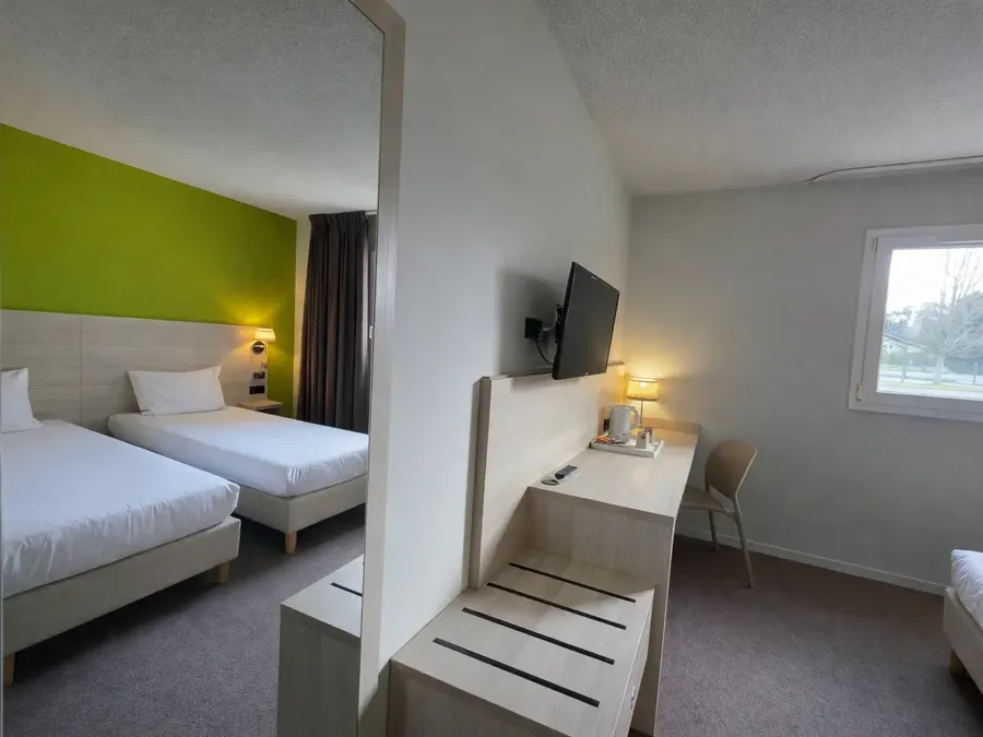 Chambre Twin moderne avec deux lits simples et télévision murale au Hotel Les Bruyères à Castets.