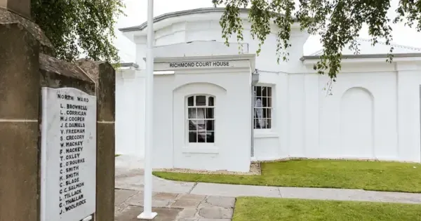 White building with window and plaque at the front with names on it