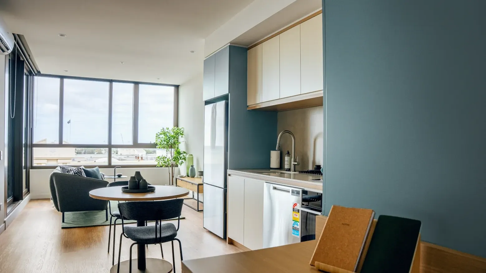 Modern apartment kitchen with dining table and large window at Caulfield Place.