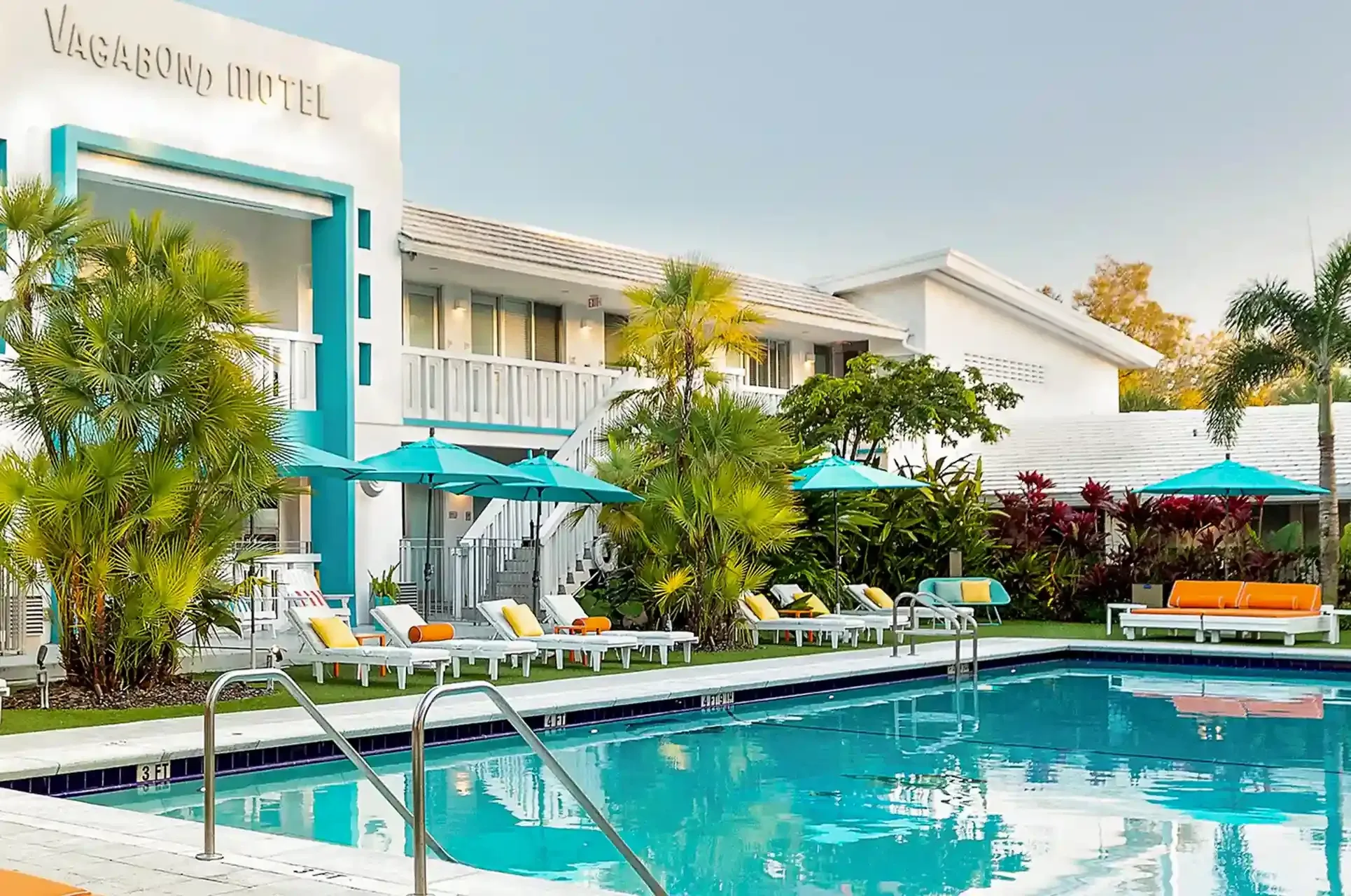 Pool courtyard at The Vagabond Hotel Miami with turquoise umbrellas, white loungers and the original Vagabond Motel facade