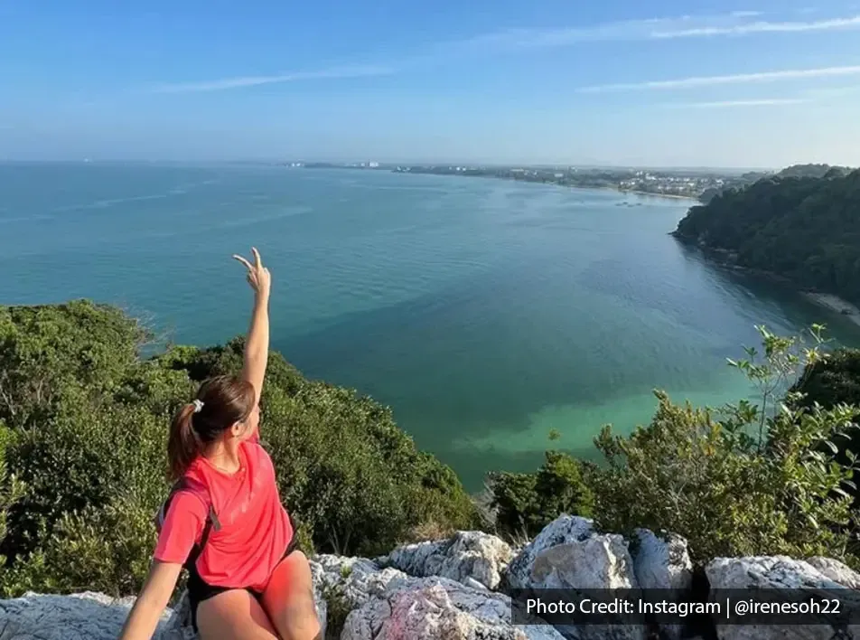 A woman sitting on a rock with a scenic sea background - Lexis MY