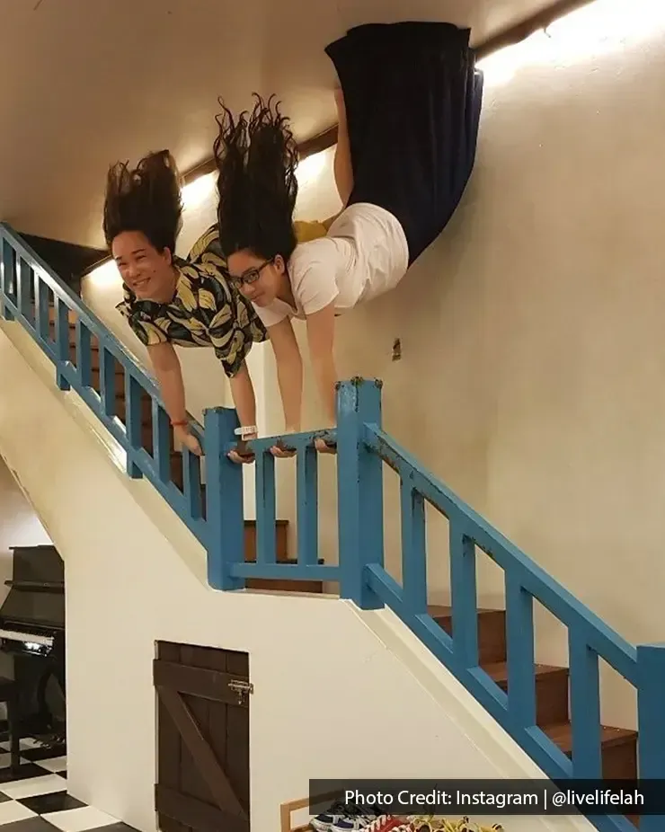 Visitors posing in Upside Down Museum illusion on staircase – Lexis Suites Penang