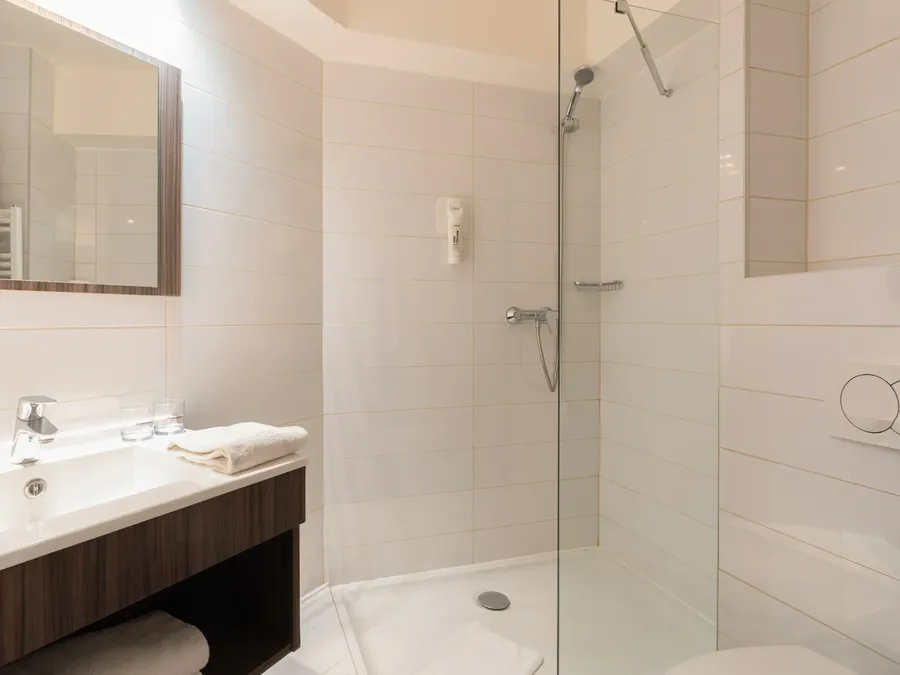 Clean and modern bathroom with shower and sink at Appart’Hôtel Hévéa, Valence.