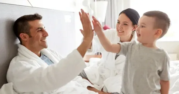 Young boy high-fives his parents in a family hotel room 