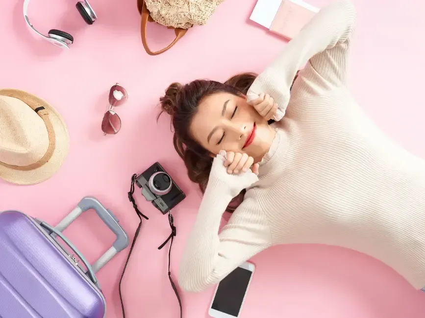 A woman smiling and lying on the floor with her travel essentials - Grand Lexis Port Dickson
