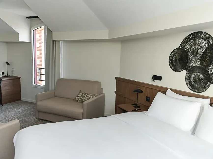 Chambre familiale confortable avec lit et canapé à l'Hôtel Rivella de Clisson.