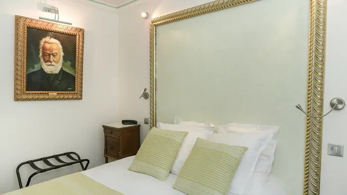 Chambre élégante avec un lit, une tête de lit décorative et un portrait à l'Hôtel Villa Aultia.