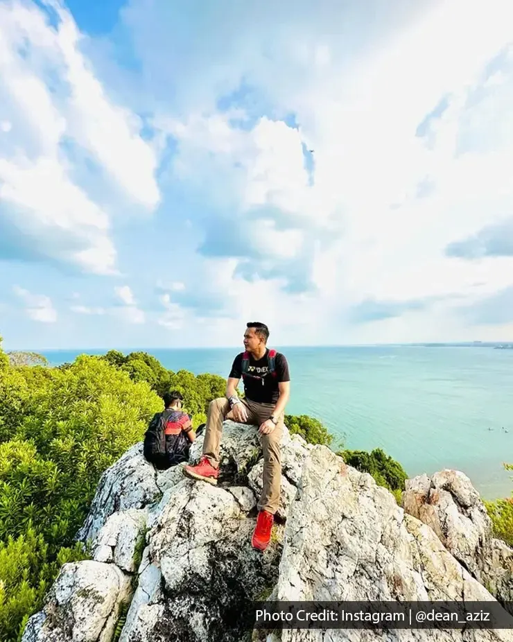 Dua lelaki berehat di atas batu bukit dengan pemandangan laut - Lexis Hibiscus Port Dickson