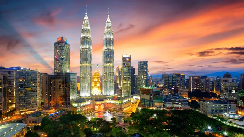 Night cityscape with skyscrapers and Petronas Twin Towers under a colorful sunset sky near Sunway Velocity Hotel