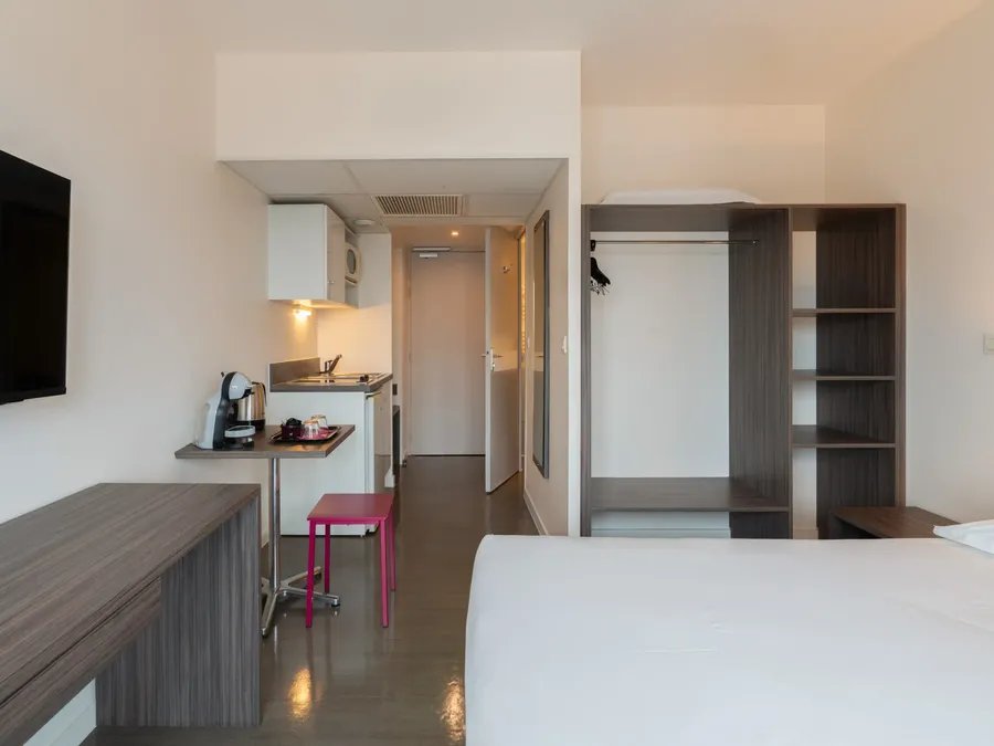 Interior of Superior Studio with kitchen, table, and large bed at Appart’Hôtel Hévéa in Valence.