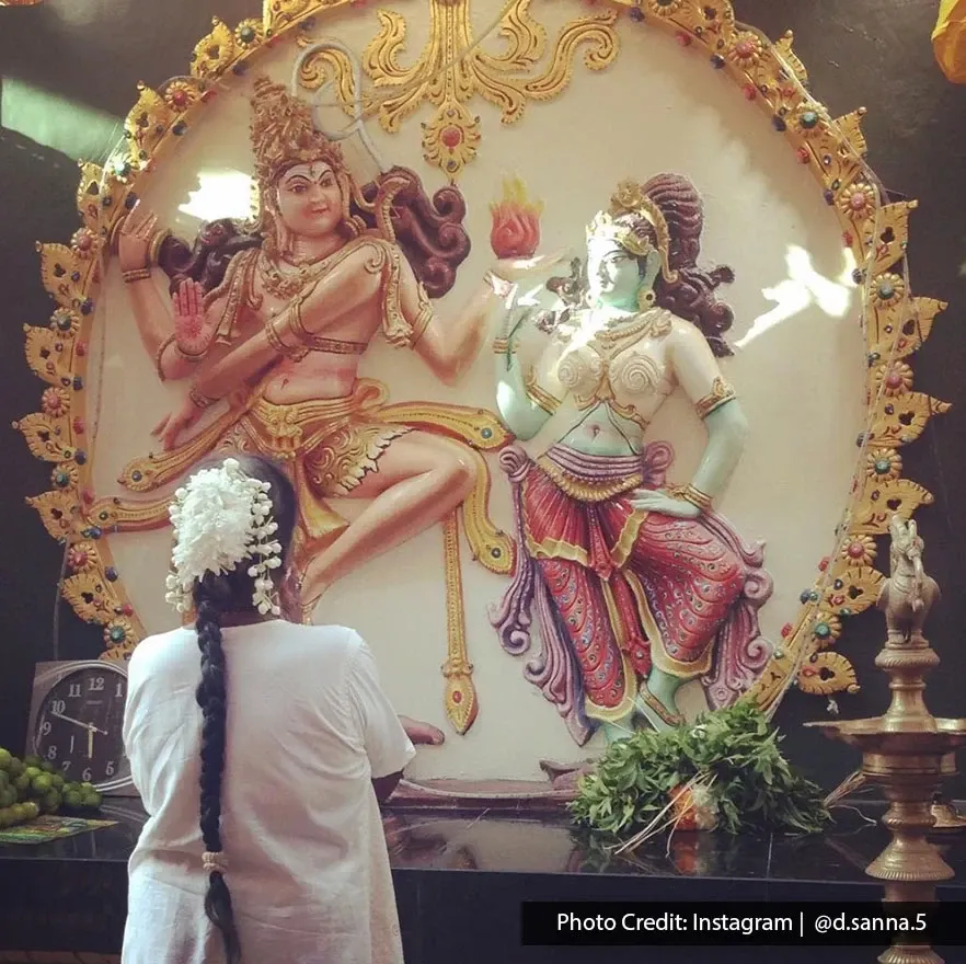 Devotee worshipping Saraswati and Ganesha inside Sri Mahamariamman Temple.
