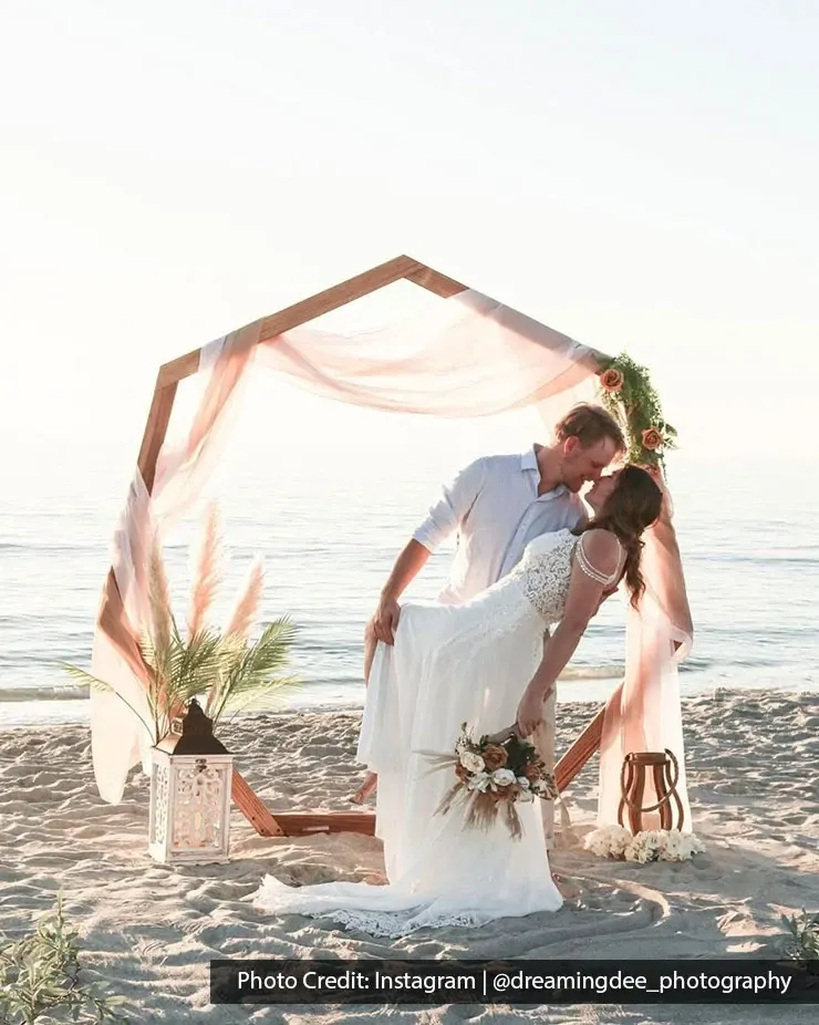 Bride and groom sharing romantic beach wedding moment by sea.