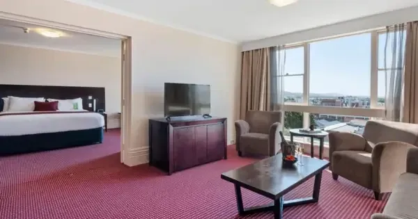 Family suite with sitting area and city view windows at Hotel Grand Chancellor Launceston