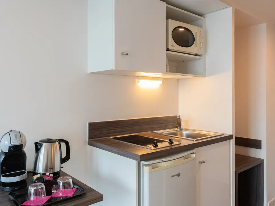 Compact kitchen setup with microwave, coffee machine, and fridge in Superior Studio at Appart’Hôtel Hévéa, Valence.