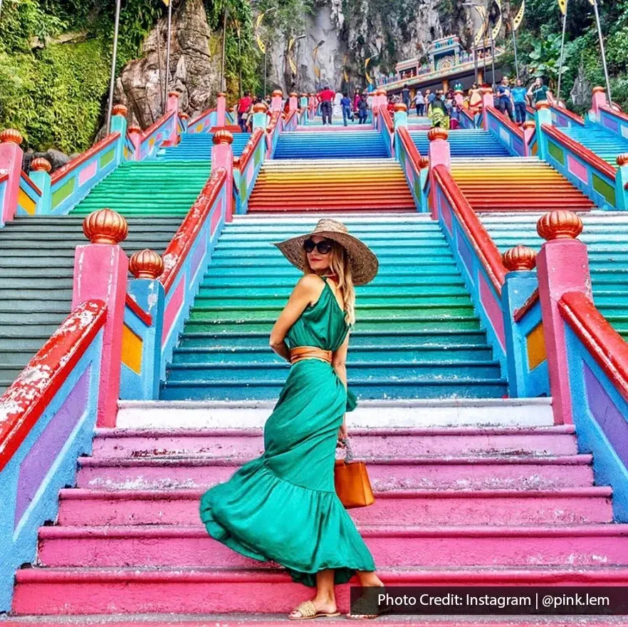 Woman posing on colourful Batu Caves staircase.