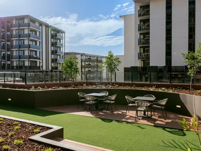 Outdoor seating area with tables and chairs surrounded by greenery at Caulfield Place.