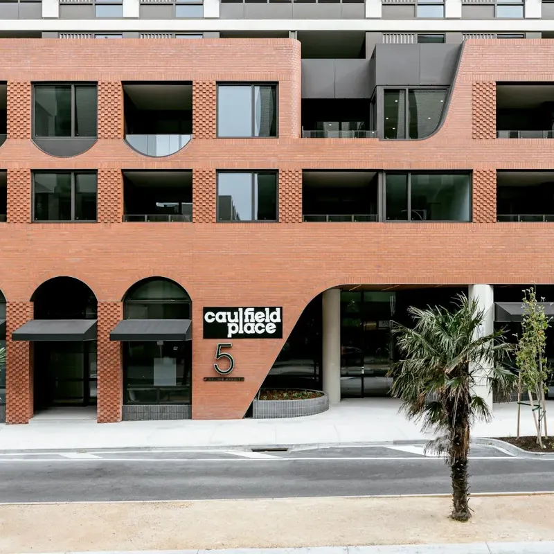 Caulfield Place building exterior with palm trees and a parked car.