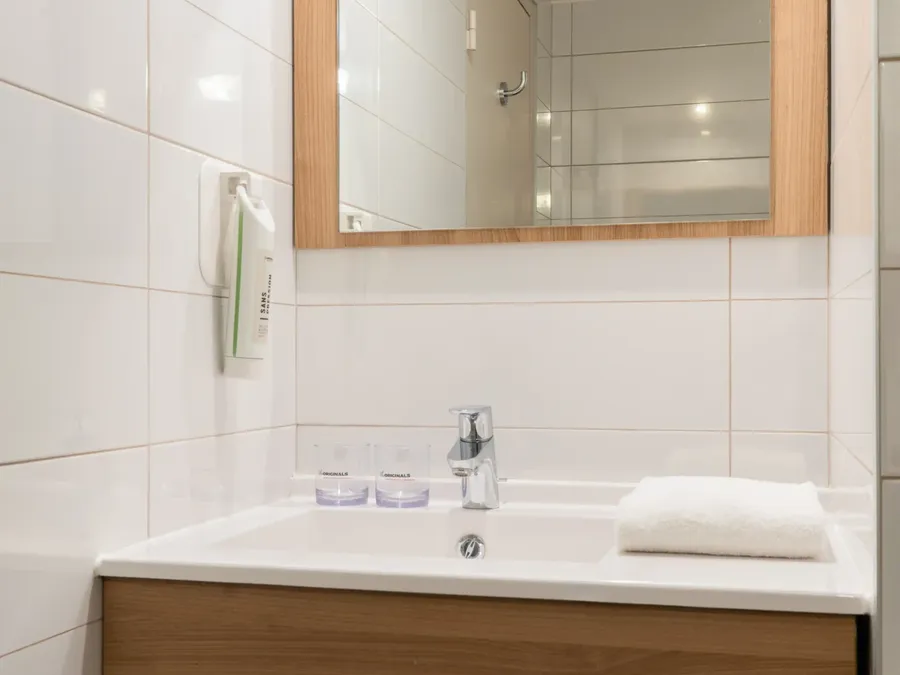White bathroom with a wooden sink and mirror at Appart’Hôtel Hévéa in Valence.