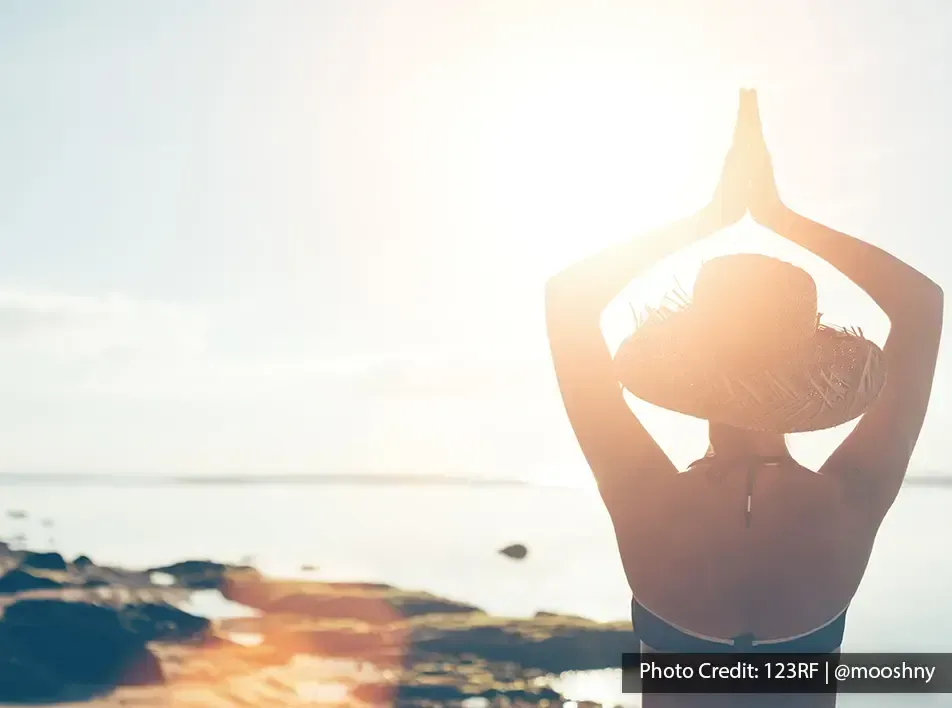 Woman practicing yoga by the sea during sunrise - Lexis Hibiscus Port Dickson