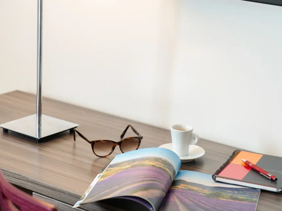 Desk with magazine, coffee, and notebook at Appart’Hôtel Hévéa, Valence.