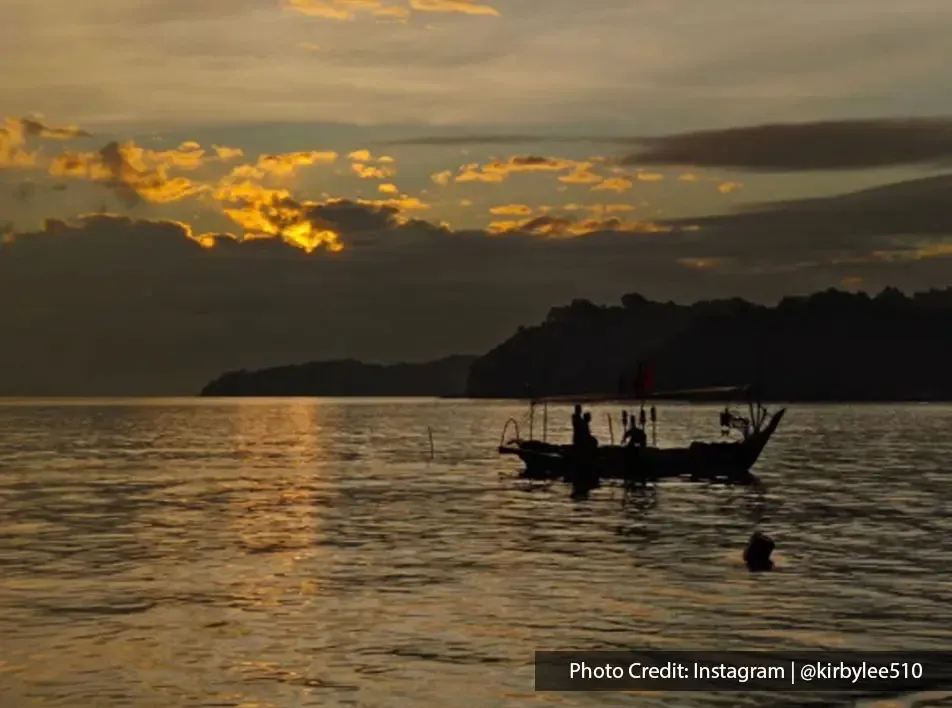 Golden sky reflecting on calm sea with boat at Teluk Kumbar Penang