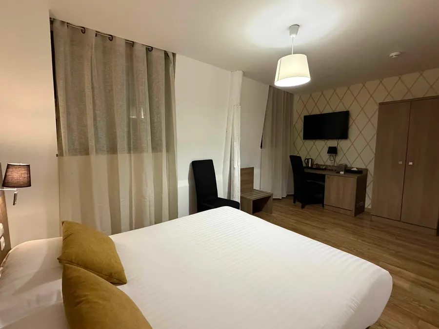 Chambre classique élégante avec lit et bureau à Le Grand Hôtel Molière de Pézenas.