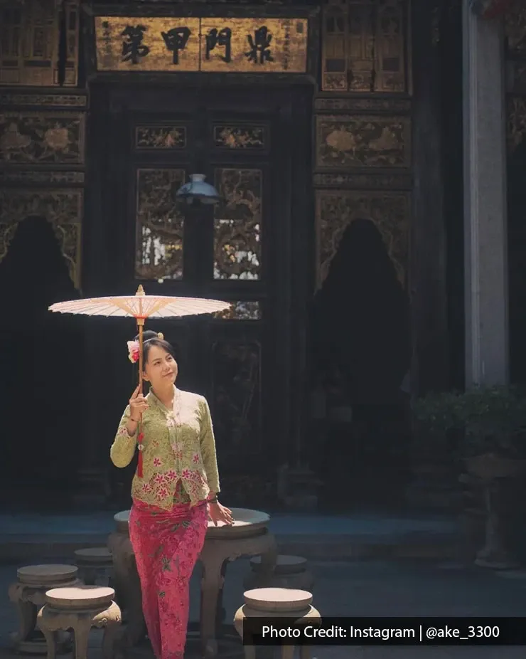 Woman in Peranakan kebaya holding umbrella inside Pinang Peranakan Mansion.