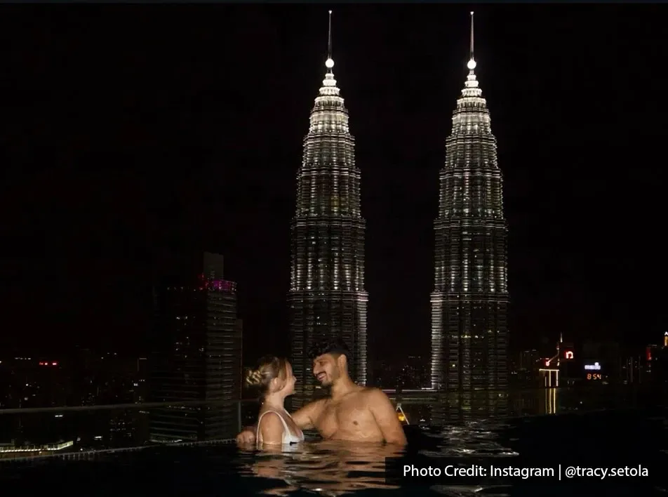 A couple relaxes in an infinity pool, with the iconic Petronas Towers towering behind them.