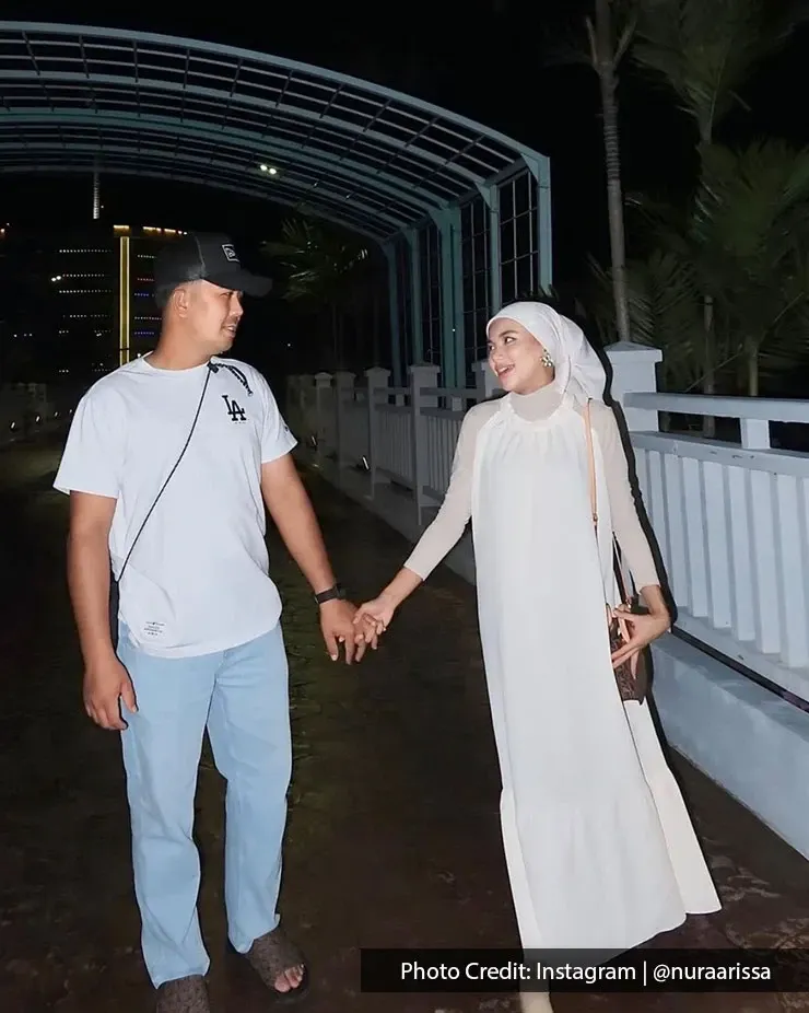 Couple holding hands while walking together at night under a covered walkway.