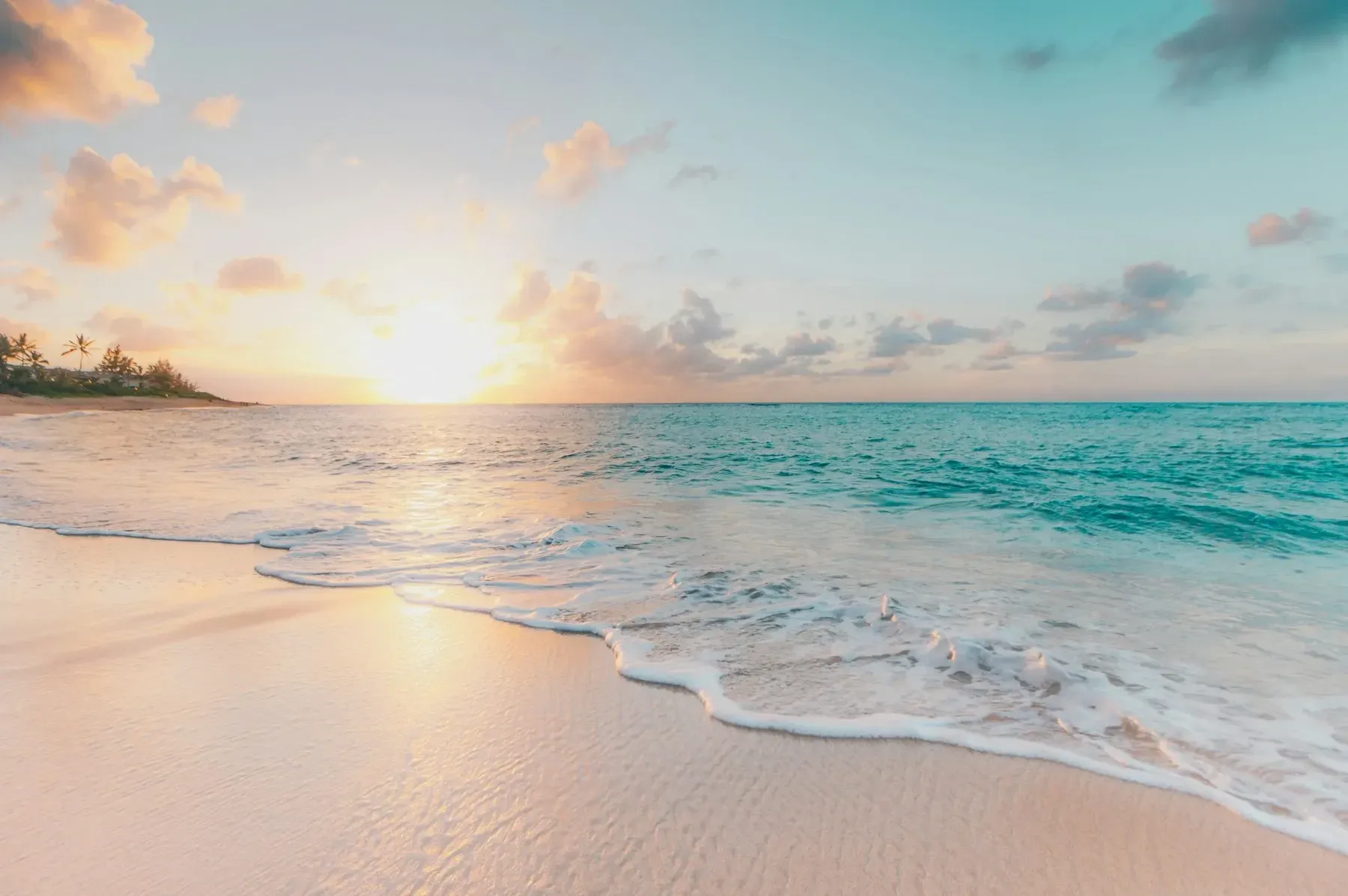 Gentle waves washing onto a sandy beach at sunset
