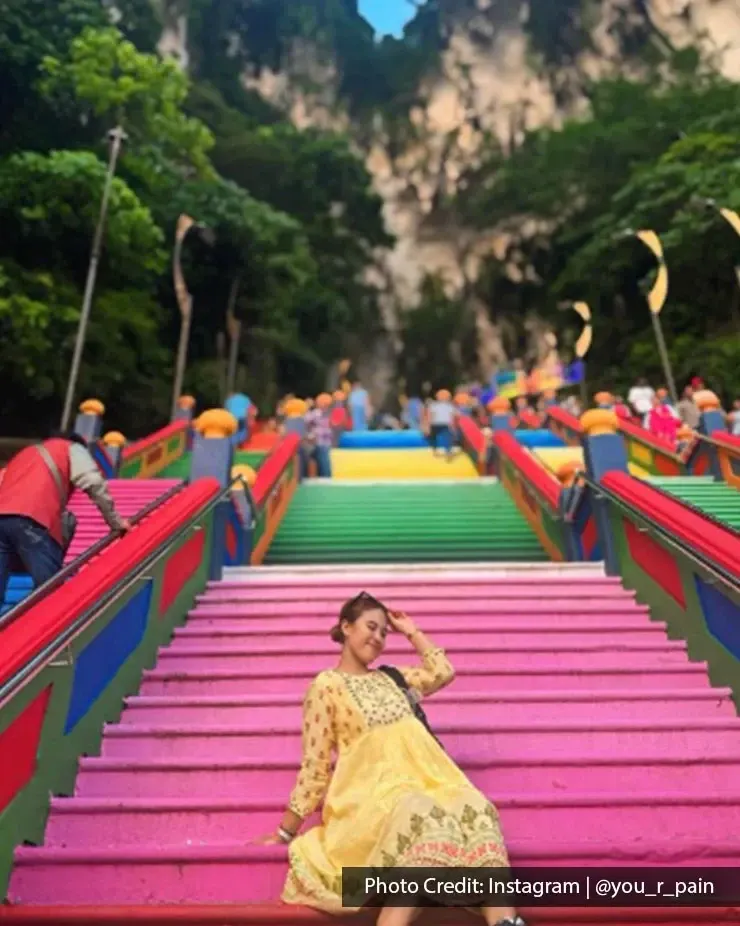 Visitor sitting on the rainbow staircase at Batu Caves