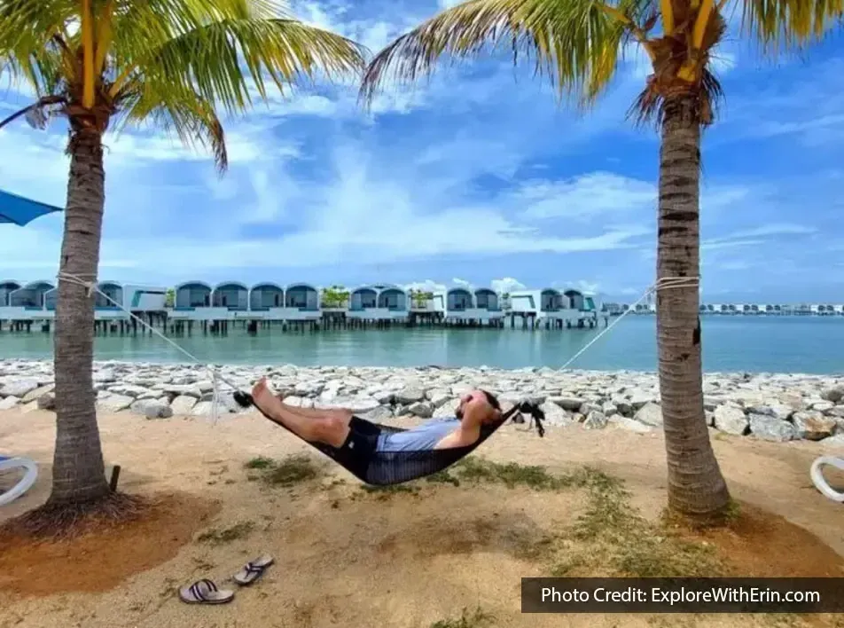 A man lying in a hammock and relaxing on the beach during his beach trip - Lexis MY