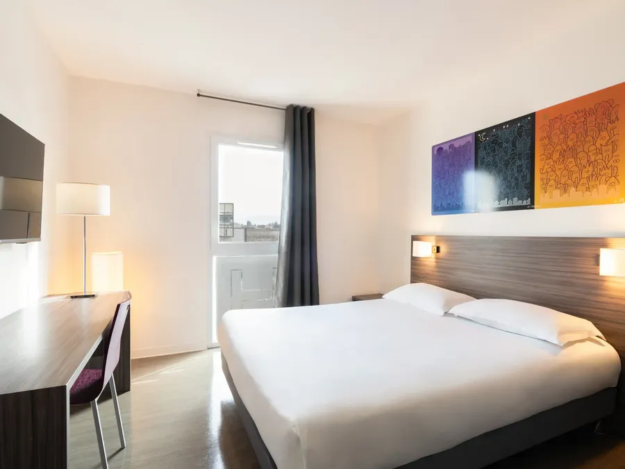 White Superior Studio bedroom with a bed, desk, and wall art at Appart’Hôtel Hévéa in Valence.