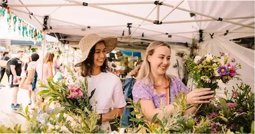 Two women looking at flowers at a Brisbane market